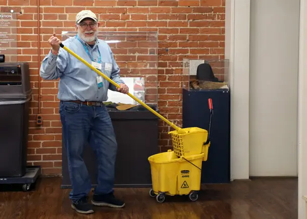 A volunteer mops the wooden floor at the Craft Center.