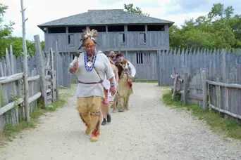 Educators in reglia demonstrate a traditional Wampanoag dance in the 17th-Centuery English Village.