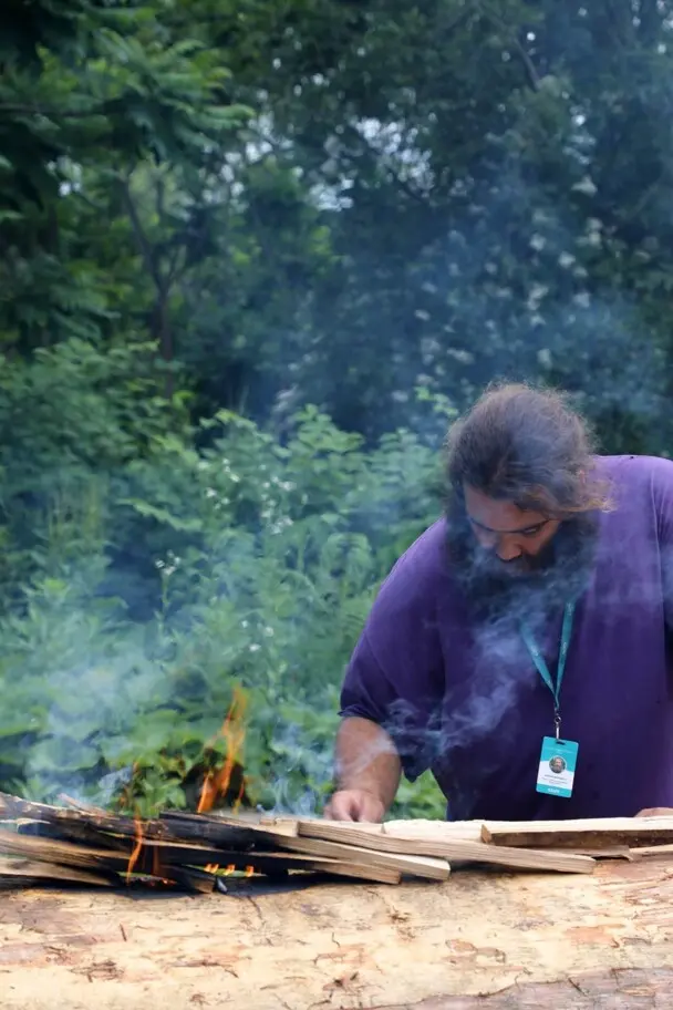 Museum educator carefully tends to the fire on the mishoon.