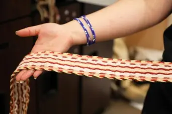 Educator holds out woven belt