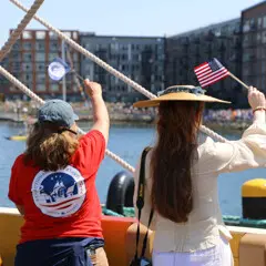 Parade of Sail Waving Flags to Spectators on Shore