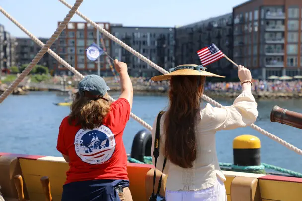 Parade of Sail Waving Flags to Spectators on Shore