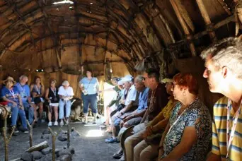 Crowd of guests seated on the fur lined benches of a wetu.