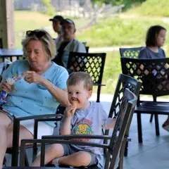 A young toddler eats ice cream with his grandmother and other guests at Plimoth Patuxet Museums.