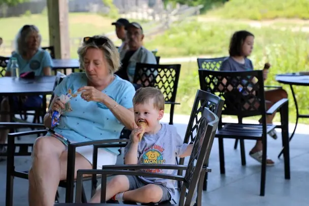 A young toddler eats ice cream with his grandmother and other guests at Plimoth Patuxet Museums.