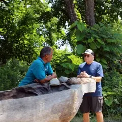 Museum guests speak with educator over the mishoon at the Historic Patuxet Homesite.