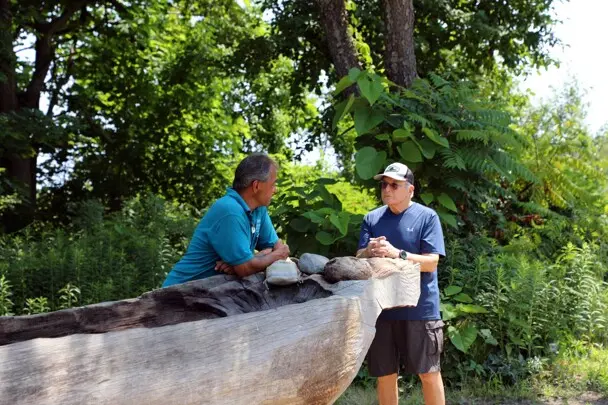 Museum guests speak with educator over the mishoon at the Historic Patuxet Homesite.