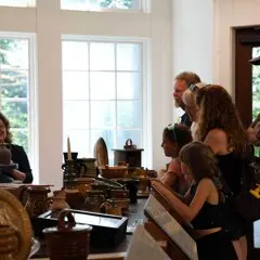 Guests gather to engage with a potter in the craft center as she works.
