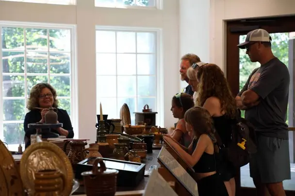Guests gather to engage with a potter in the craft center as she works.