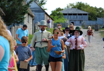 Young guests lead Pilgrim bride and her parents down the main street of the 17th-Century English Village.