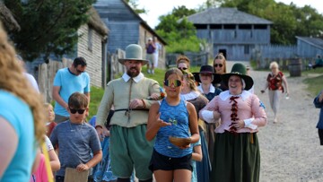 Young guests lead Pilgrim bride and her parents down the main street of the 17th-Century English Village.