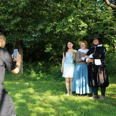 Museum guest poses with the Pilgrim couple as someone takes their photo.
