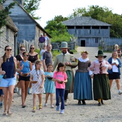 Museum guests lead Pilgrim bride and her family down the main street of the 17th-century English Village.