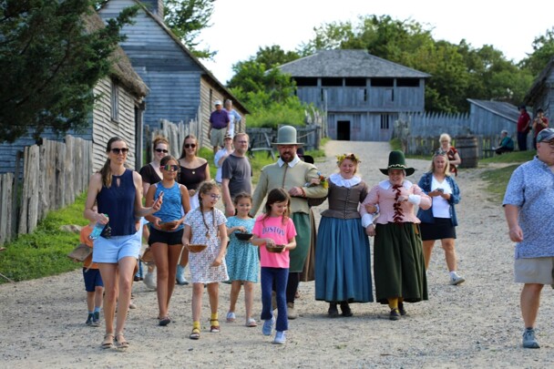 Museum guests lead Pilgrim bride and her family down the main street of the 17th-century English Village.