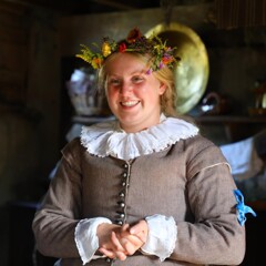 Pilgrim bride smiles inside house while wearing flower crown.
