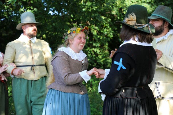 Pilgrim bride and groom join hands during wedding ceremony.