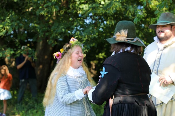 Pilgrim bride holds the groom's hands and smiles widley as they are married.
