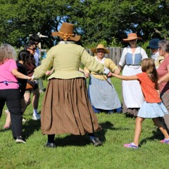 Pilgrims and Museum guests join hands and dance in a circle on the Village Green.