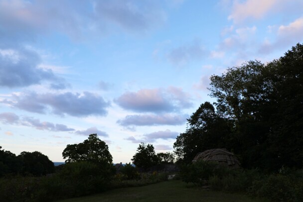 The post-contact wetu on a hill at dusk.