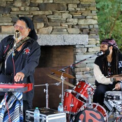 The Groovalottos lead singer and drummer both sing into microphones.