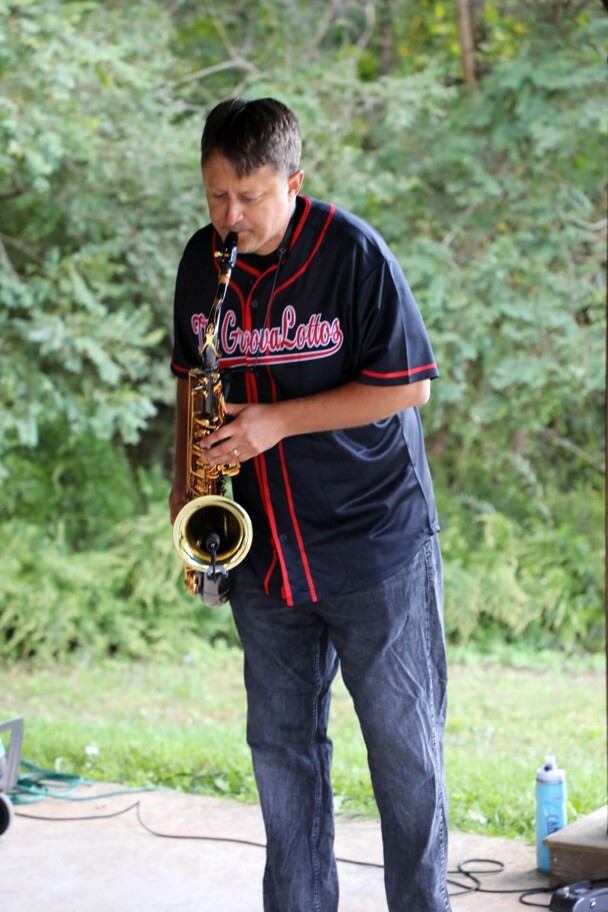 A member of The GroovaLottos plays the saxophone.
