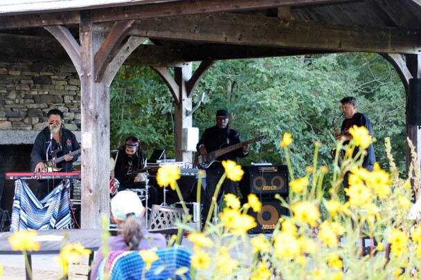 The GroovaLottos perform at the Craft Center Pavillion. Yellow flowers are at the foreground.