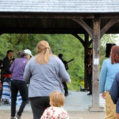 A group of women and children dance to live music.