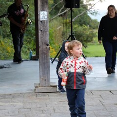 A mother follows her young child who is running after another young child to play.