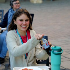A seated young woman smiles as she opens a bottle of diet coke at The Best Night of the Week.