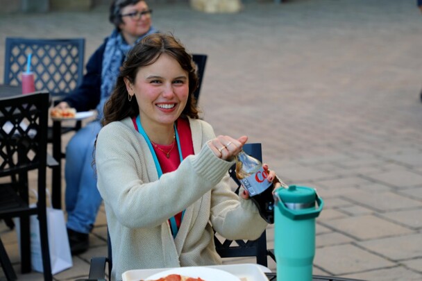 A seated young woman smiles as she opens a bottle of diet coke at The Best Night of the Week.