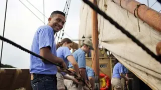 Four people work together to pull rope on deck of Mayflower