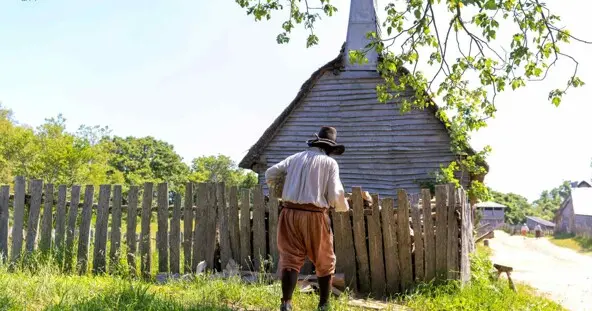 Pilgrim man works in front of a grey house