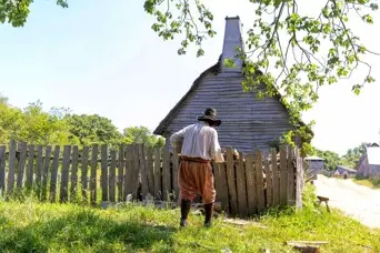 Pilgrim man works in front of a grey house