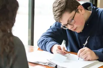 Student takes notes at a desk
