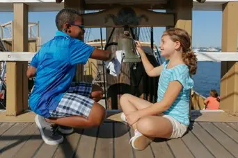 Two children clean a bell on the decks of Mayflower II
