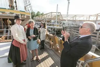 Guest poses for with a female pilgrim aboard Mayflower II.