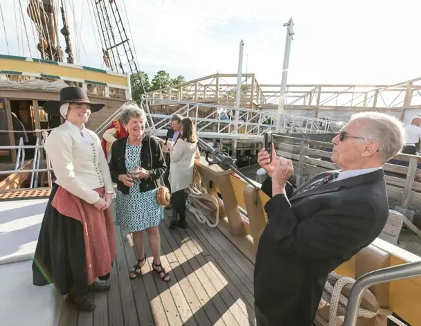 Guest poses for with a female pilgrim aboard Mayflower II.