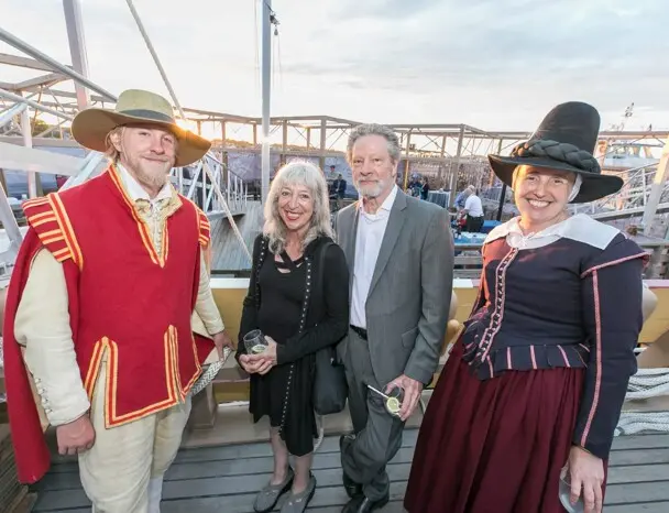 Chris Cooper and Marianne Leone pose with a female pilgrim and male pilgrim aboard Mayflower II.