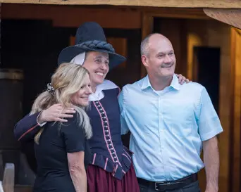 Guests pose for a photo with a female pilgrim aboard Mayflower II.