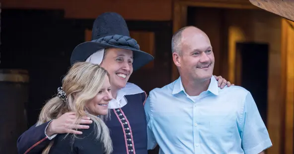 Guests pose for a photo with a female pilgrim aboard Mayflower II.